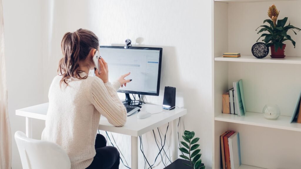 man talks on phone and points at computer screen