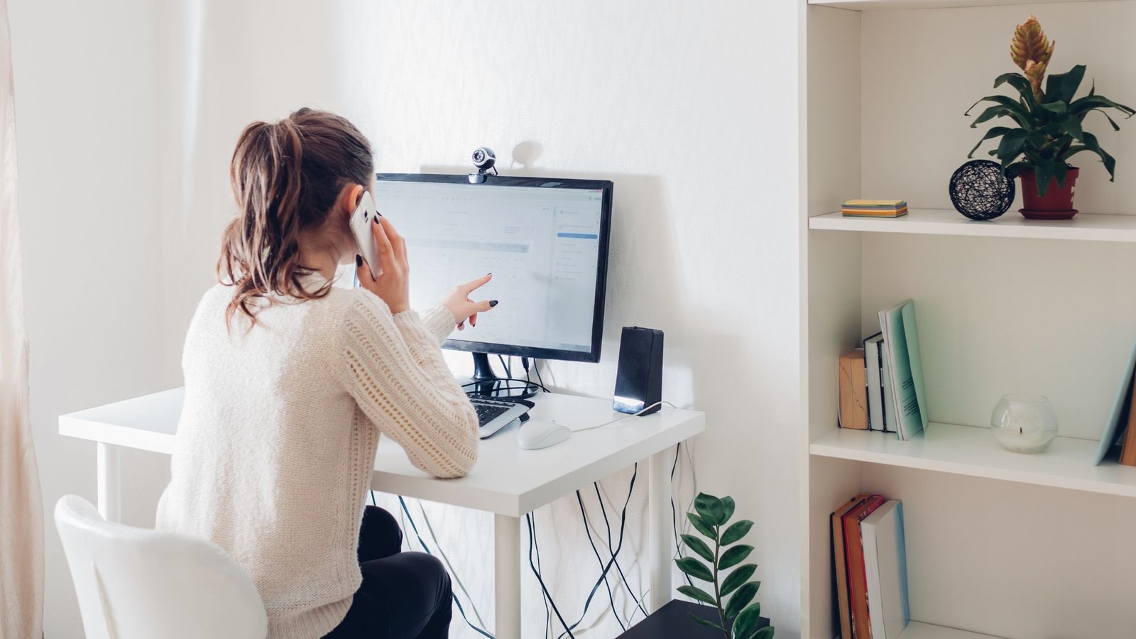 man talks on phone and points at computer screen