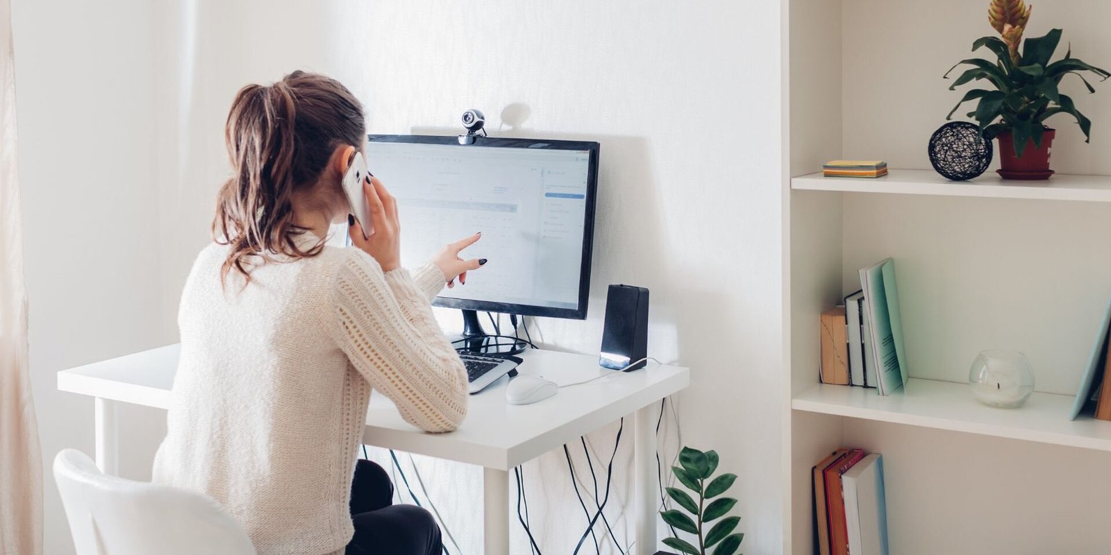 man talks on phone and points at computer screen